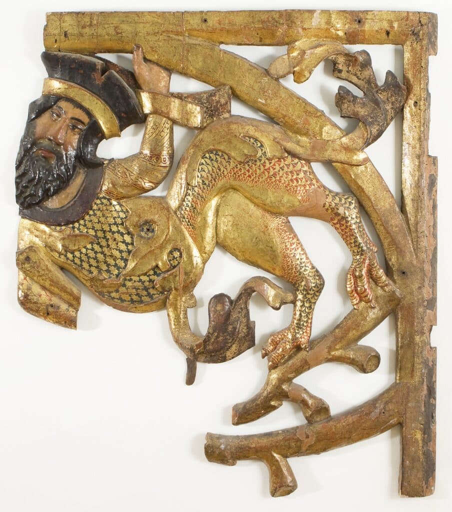Relleu de fusta daurada i policromada amb una figura barbuda i un animal fantàstic de cos escatat en vermell i or, d'estil romànic tardà.