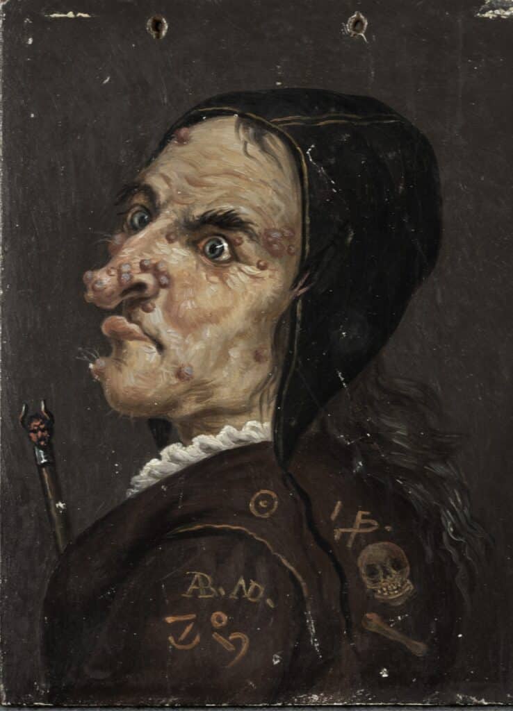 Pintura sobre fusta d'un rostre de bruixa amb trets grotescos i símbols màgics a la roba, d'estil popular barroc.