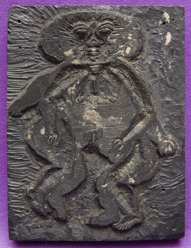 Matriu de fusta per a xilografia amb la figura d'una persona esculpit en relleu, amb traços incisats detallats.