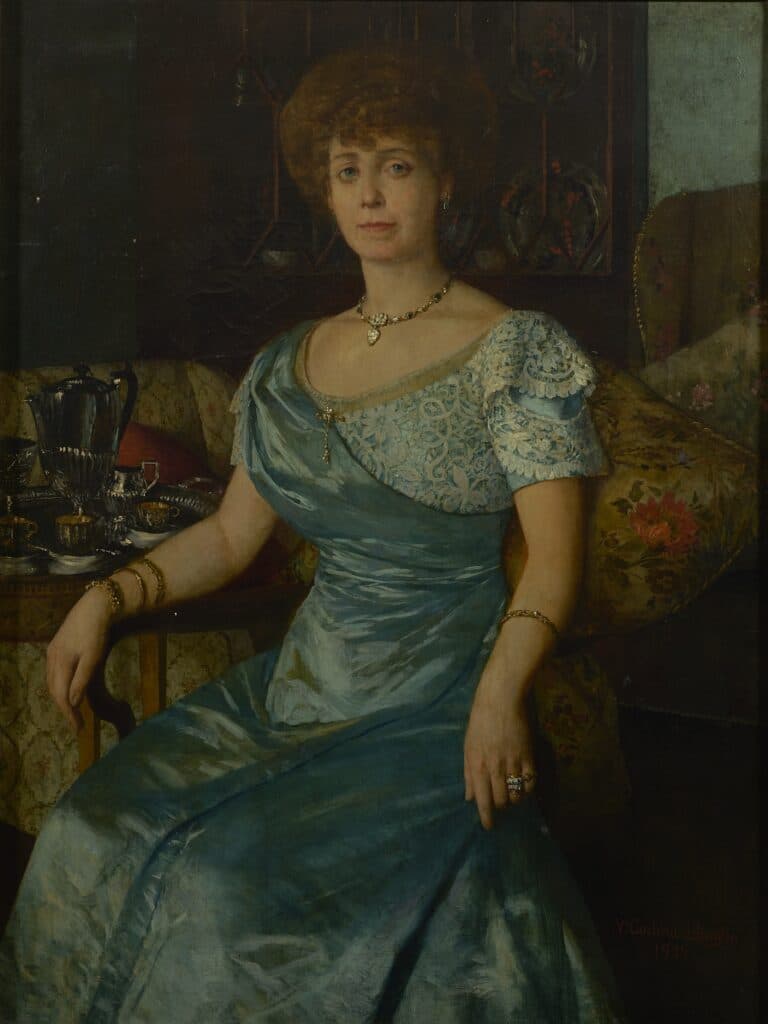 Retrat a l'oli d'una dona elegant vestida amb un vestit blau satí i puntes, asseguda en un sofà, amb una vaixella de plata al costat