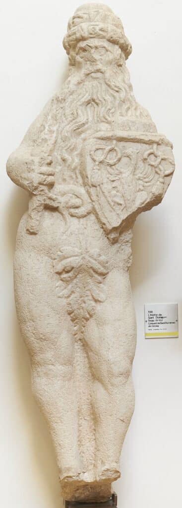 Escultura de pedra calcària d'un home barbut dempeus, amb escut heràldic, procedent del Convent de Sant Domènec de Girona.