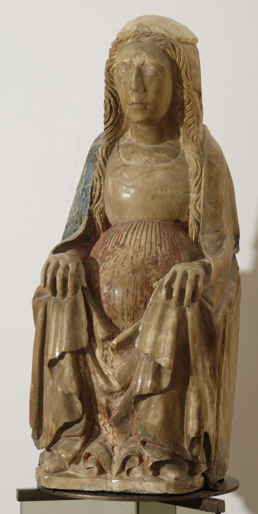 Escultura de pedra policromada que representa la Mare de Déu asseguda en tron, de tipologia romànica tardana o gòtica primerenca. La figura, amb els cabells llargs ondulats i vel, vesteix mantell blau i túnica amb plecs verticals en vermell. Les mans reposen sobre els genolls i està visiblement embarassada. Conserva restes de policromia original