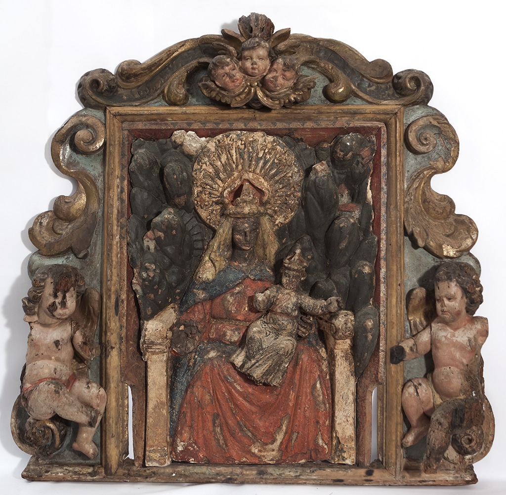 Relleu en fusta policromada que representa una Mare de Déu entronitzada amb el Nen Jesús. Relleu barroc daurat amb querubins als costats i a la part superior.
