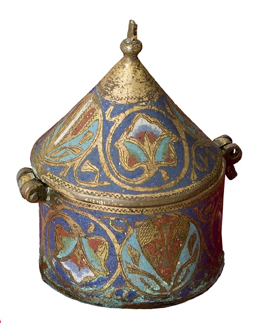 Pixis de coure daurat i esmalts de colors de forma cilíndrica, amb tapadora cònica rematada per un pom metàl·lic. Decorat amb motius vegetals entrellaçats sobre fons blau, amb esmalts en tons turquesa, vermell i blanc. Als costats presenta dues anelles de suspensió. Peça d'orfebreria religiosa medieval d'estil romànic.