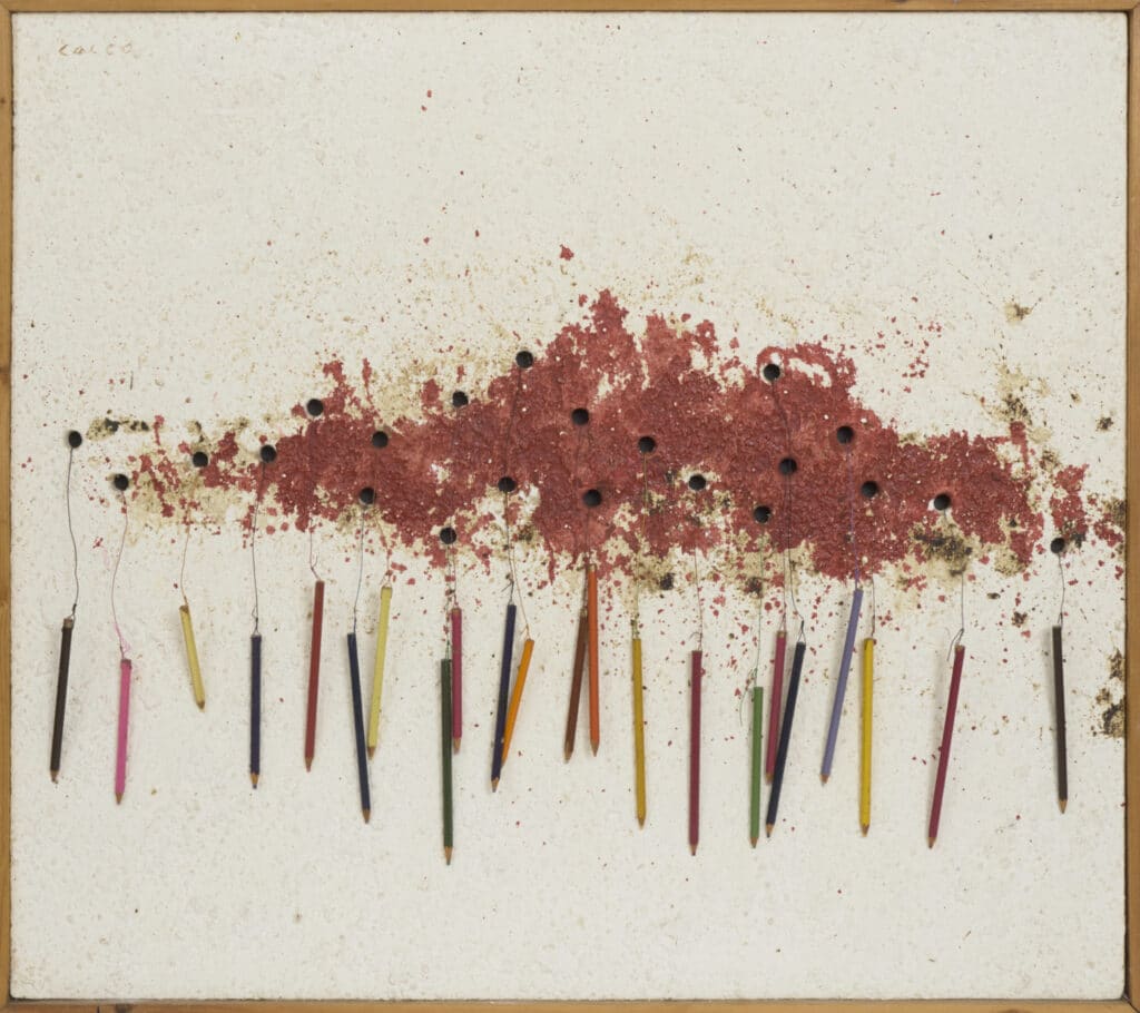 Assemblage amb llapis de colors clavats verticalment i taca vermella amb forats negres a la part superior sobre fons blanc