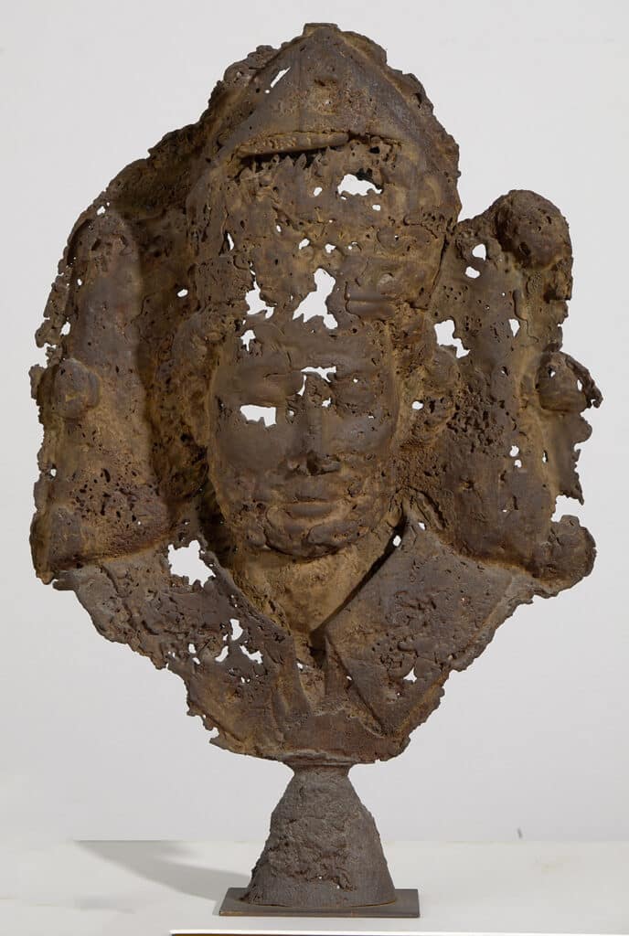 Bust escultòric erosionat amb textura porosa i forats, representació fragmentada d'un rostre sobre pedestal, escultura contemporània en material deteriorat