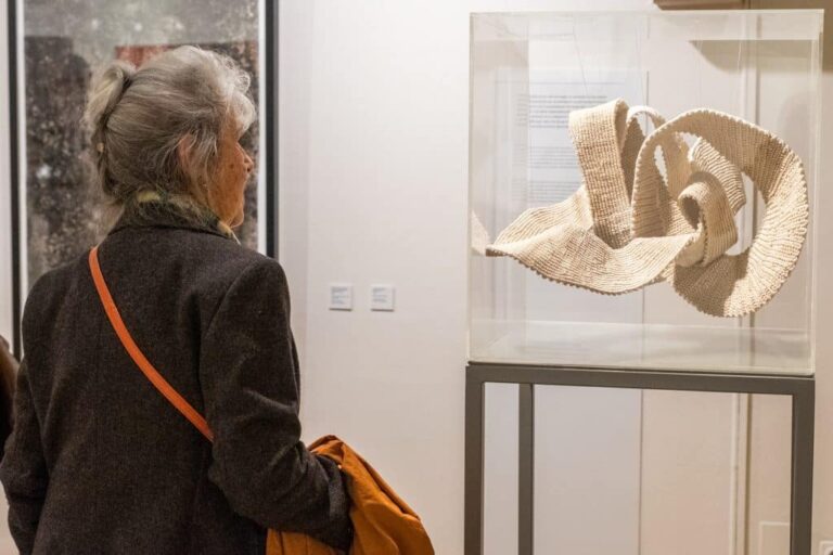 Dona contemplant una obra dins d'una vitrina