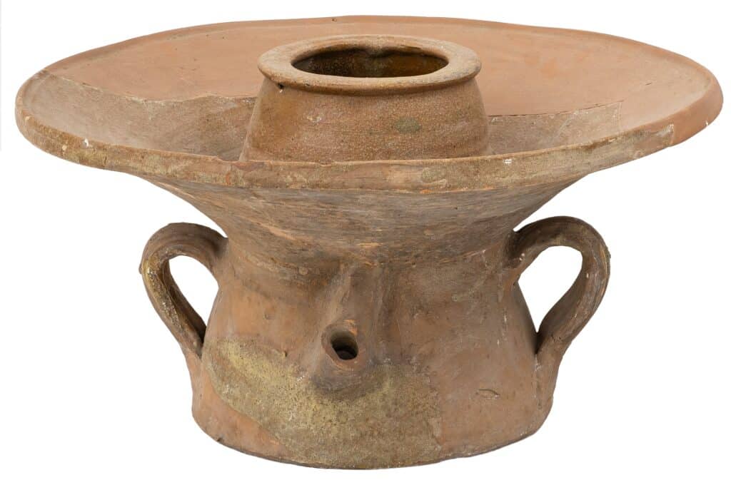 Recipient de terrissa amb dues nanses i una obertura central, de forma ampla i base robusta, amb restes de vernís marró.