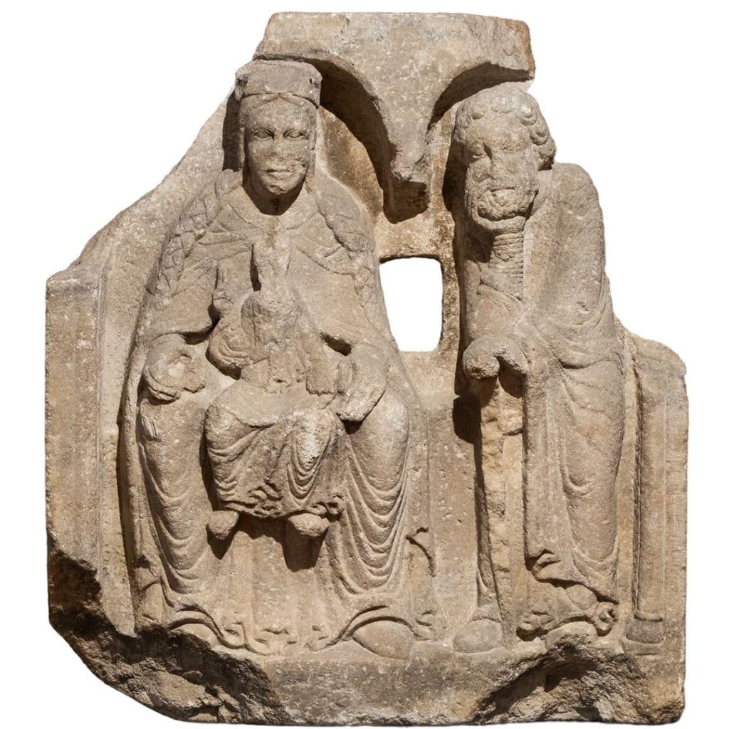 Relleu en pedra romànic de la Verge amb el Nen asseguda i sant Josep dret, sota arcades, escultura medieval fragmentada